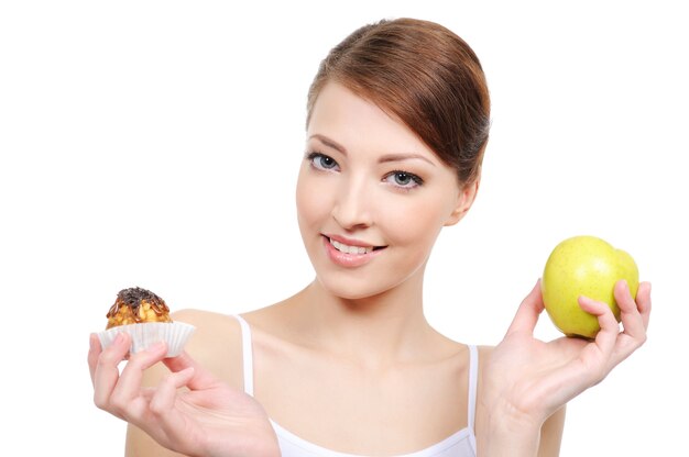 Young beautiful woman choosing between sweets and healthy food