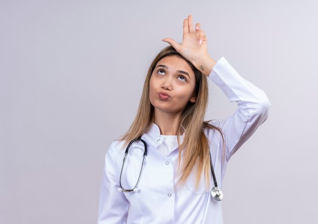聴診器で白衣を着てゆるく身振りで示す若い美女医師が頭上で手で歌う