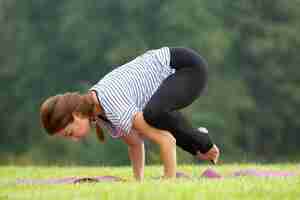 Free photo young beautiful woman doing yoga exercise in green park. healthy lifestyle and fitness concept.