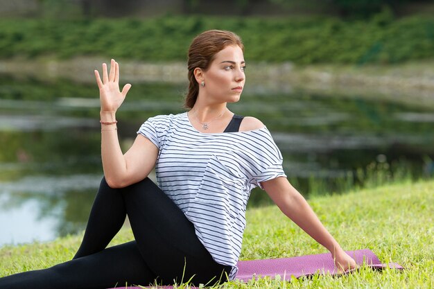 Young beautiful woman doing yoga exercise in green park