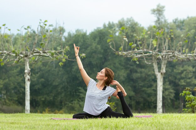 Young beautiful woman doing yoga exercise outdoors