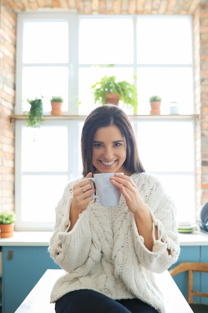 Young beautiful woman drinking a hot drink in the kitchen