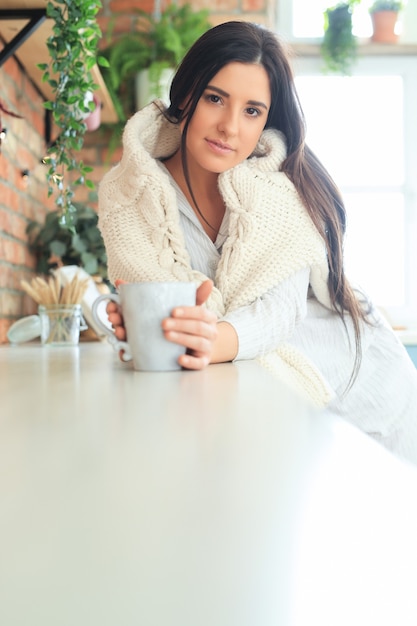 Young beautiful woman drinking a hot drink in the kitchen