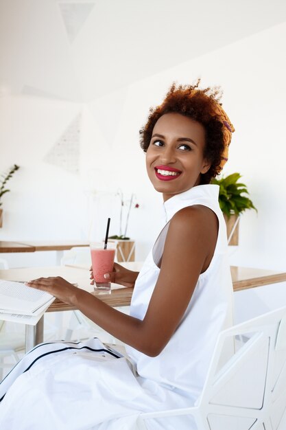 Young beautiful woman drinking smoothie smiling resting in cafe