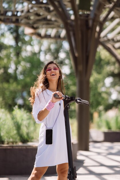 Young beautiful woman and an electric scooter ecological transport