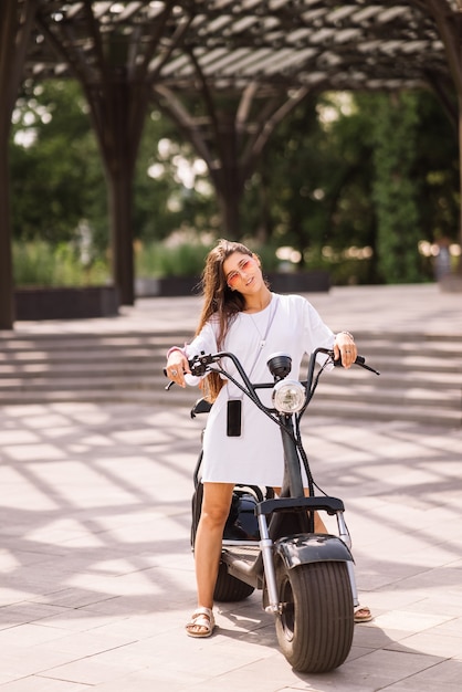 Foto gratuita giovane bella donna e uno scooter elettrico, trasporto ecologico