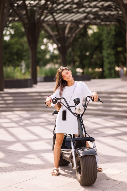 Free photo young beautiful woman and an electric scooter, ecological transport