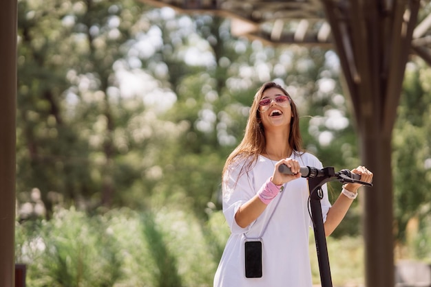 Giovane bella donna e uno scooter elettrico, ragazza moderna, nuova generazione, trasporto elettrico, trasporto ecologico