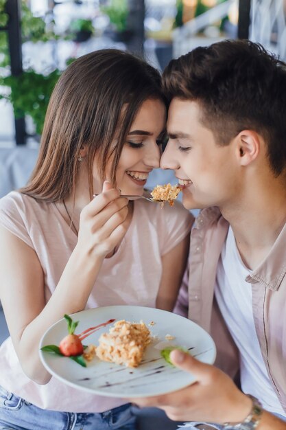 Young beautiful woman feeds her boyfriend with a delicious cake