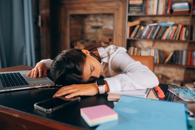 若い美しい女性は彼女の机で眠りに落ちました