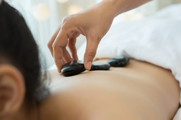 Young beautiful woman getting hot stone spa treatment.