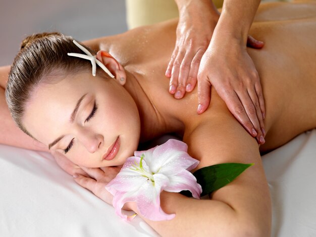 Young beautiful woman getting relaxing shoulder massage in beauty salon - indoors