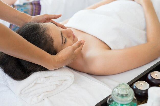 Young beautiful woman having face massage relaxing in spa.