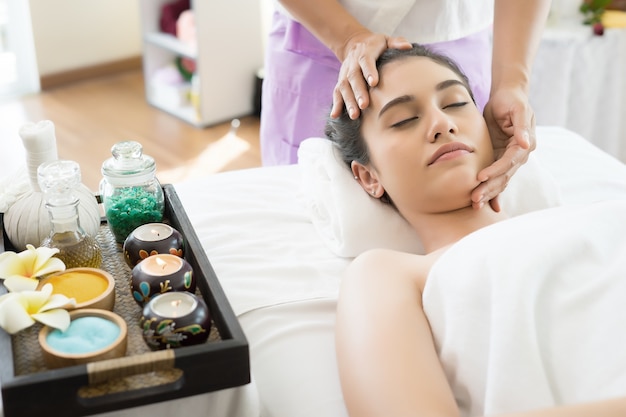 Free photo young beautiful woman having face massage relaxing in spa.