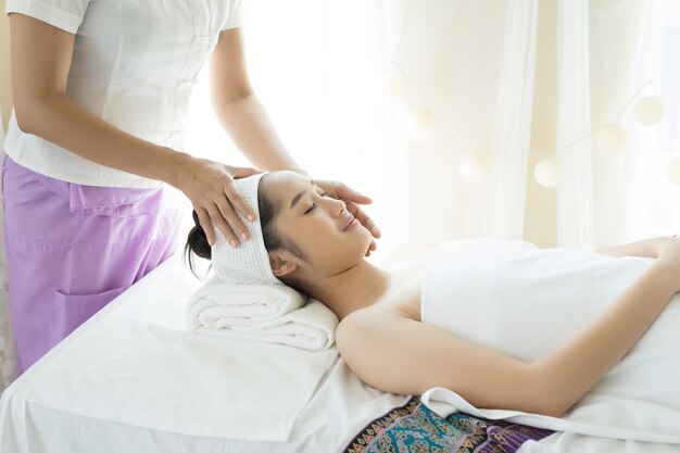 Young beautiful woman having face massage relaxing in spa.