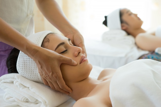 Young beautiful woman having face massage relaxing in spa.