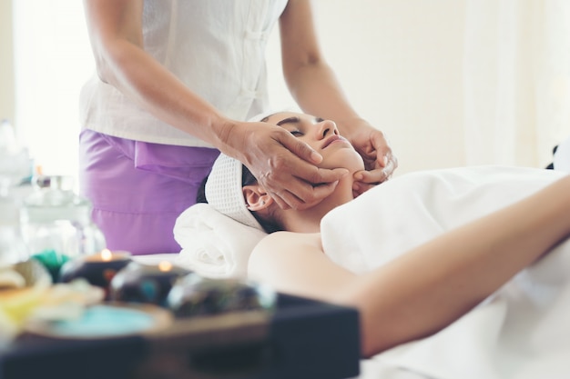 Young beautiful woman having face massage relaxing in spa.