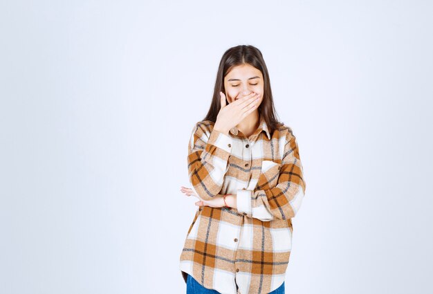 young beautiful woman holding her laugh on white wall. 