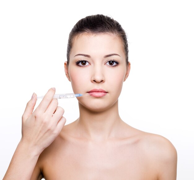 Young beautiful woman holding medical syringe near the lips  