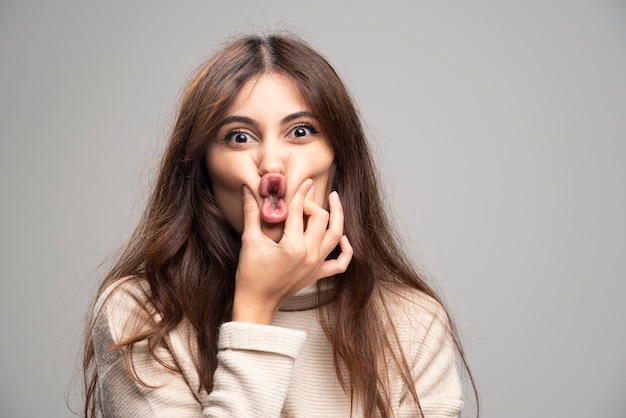 Young beautiful woman holding mouth and lips shut as zip with fingers.