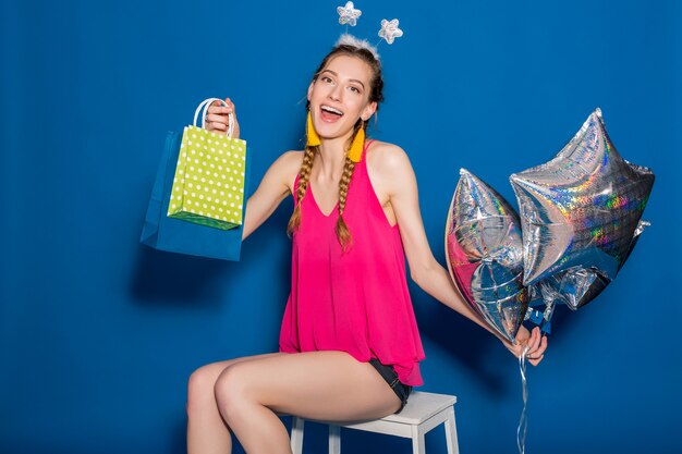 Young beautiful woman holding shopping bags and balloons