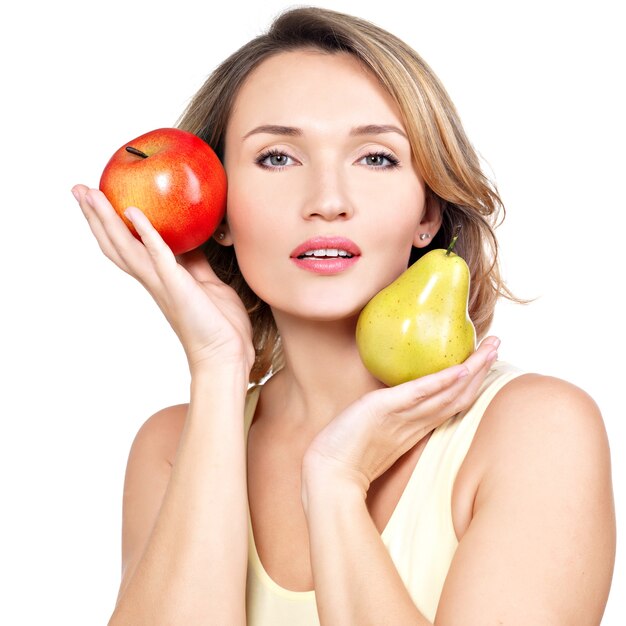 Молодая красивая женщина держит яблоко и грушу, изолированные на белом.