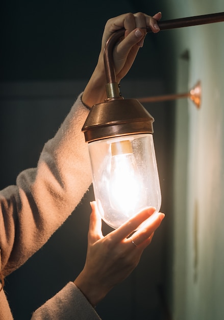 Young beautiful woman holds in her hand a small wall lamp