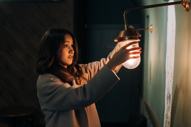 Free photo young beautiful woman holds in her hand a small wall lamp