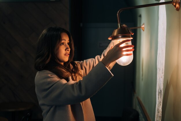 Young beautiful woman holds in her hand a small wall lamp