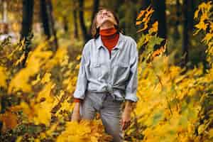 Бесплатное фото Молодая красивая женщина в осеннем парке, полном листьев