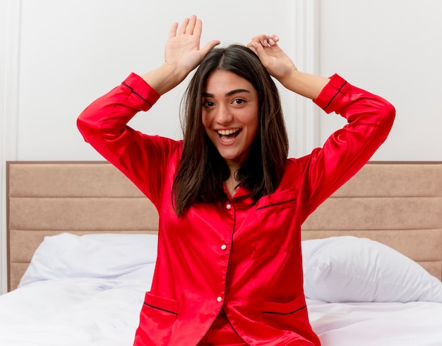 Бесплатное фото Молодая красивая женщина в красной пижаме, расслабляясь в постели