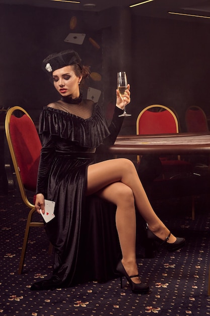 Free photo young beautiful woman is posing against a poker table in luxury casino.