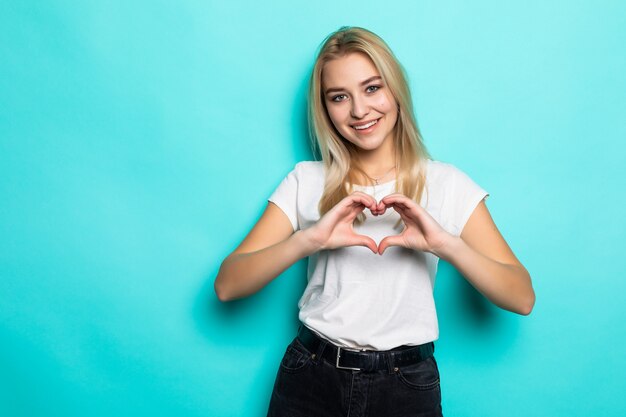 Young beautiful woman over isolated blue wall smiling in love showing heart symbol and shape with hands. Romantic concept.