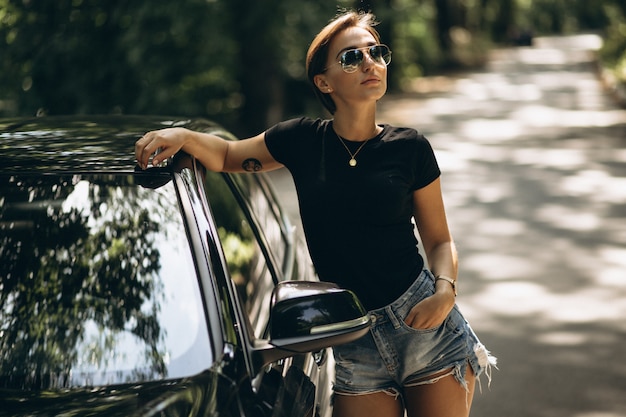 Young beautiful woman leaning on car