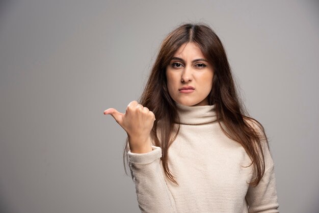 Young beautiful woman looking and pointing to the side with thumb up.