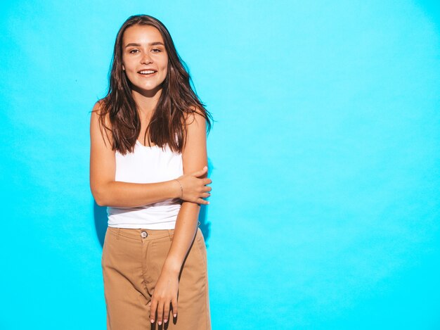 Young beautiful woman looking. Trendy girl in casual summer clothes. Funny and positive female posing near blue wall