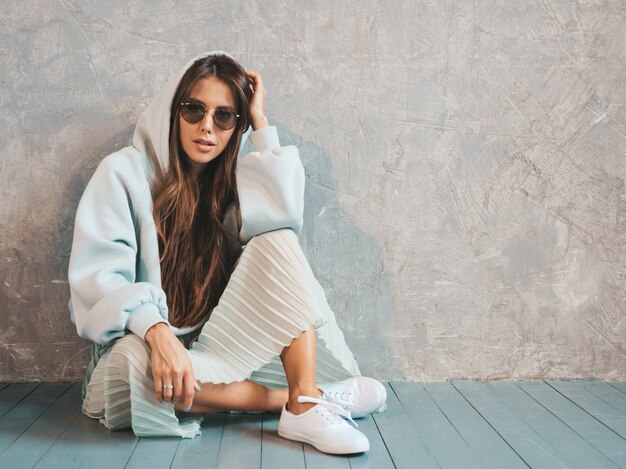 Young beautiful woman looking . Trendy girl in casual summer hoodie and skirt clothes.   sitting on the floor