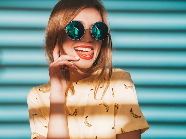 Young beautiful woman looking . Trendy girl in casual summer yellow T-shirt clothes.  and showing tongue