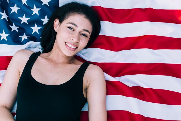アメリカの国旗の上に横たわる若い美しい女性