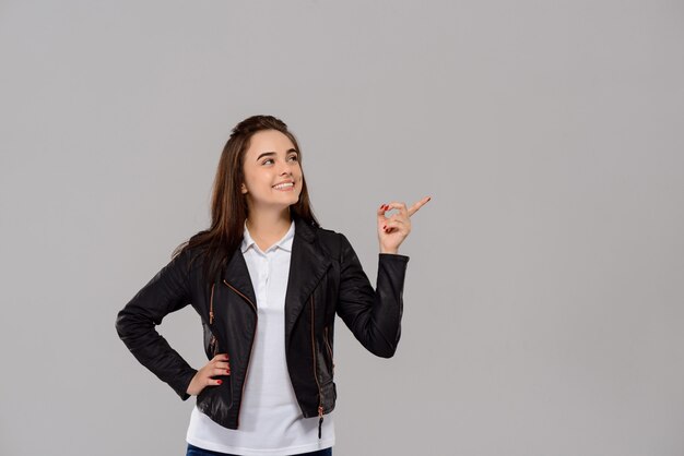 Young beautiful woman pointing finger in side over purple wall