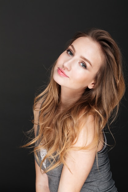 Young beautiful woman posing over dark wall