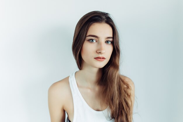 Young beautiful woman posing on a white wall