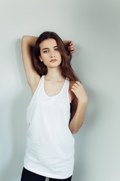 Young beautiful woman posing on a white wall