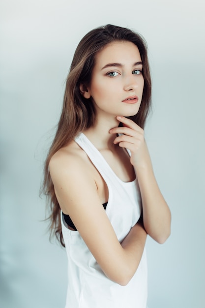 Young beautiful woman posing on a white wall