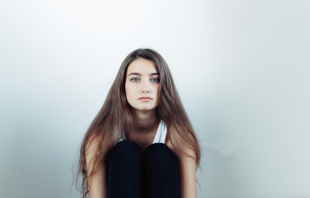 Young beautiful woman posing on a white wall