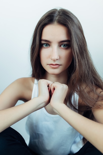 Young beautiful woman posing on a white wall