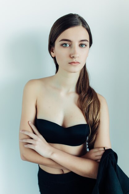 Young beautiful woman posing on a white wall