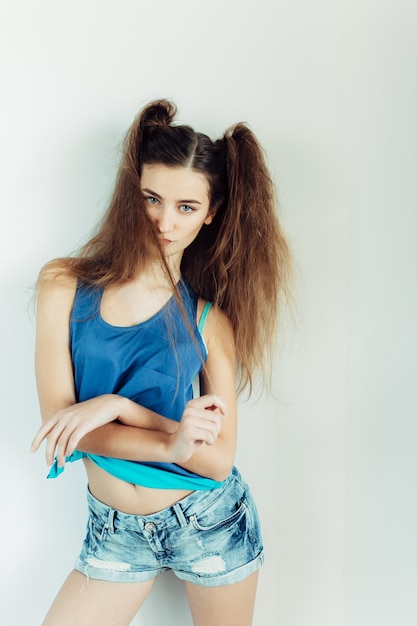 Young beautiful woman posing on a white wall