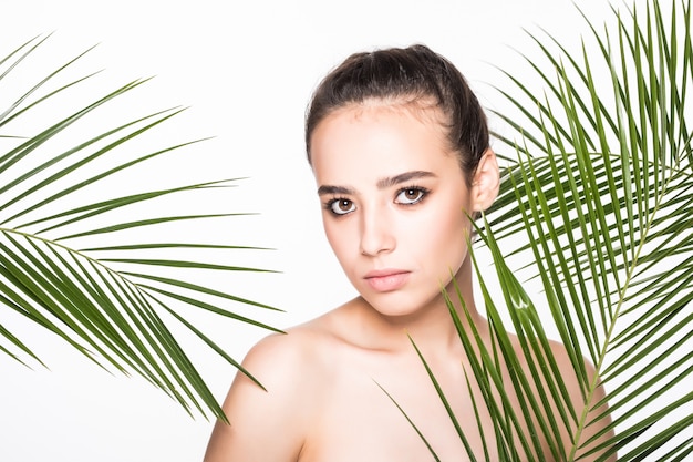 Young beautiful woman posing with green palm leaves