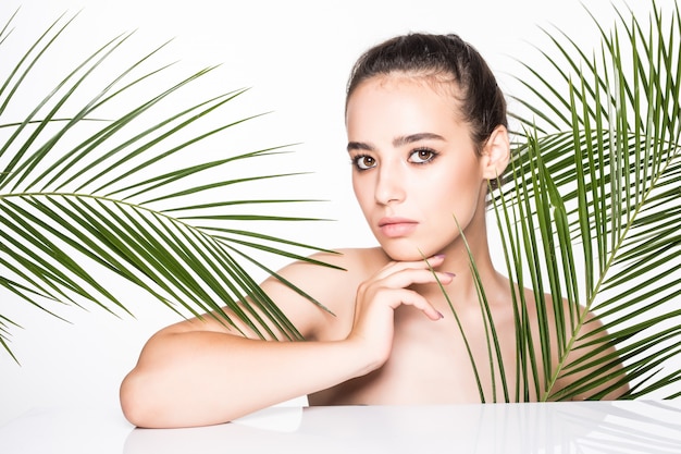 Молодая красивая женщина позирует с зелеными пальмами